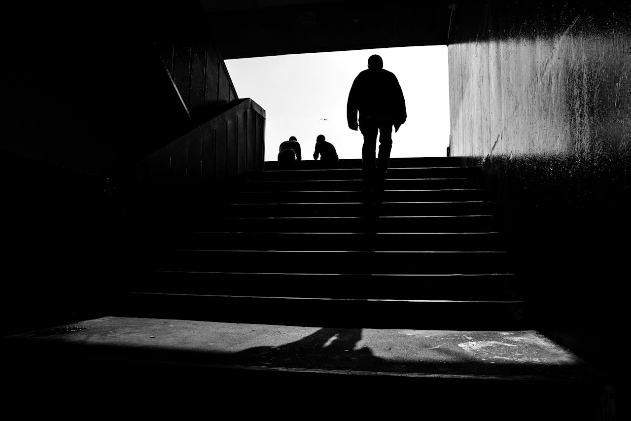 A striking black and white silhouette of a person walking upstairs, creating a moody atmosphere.