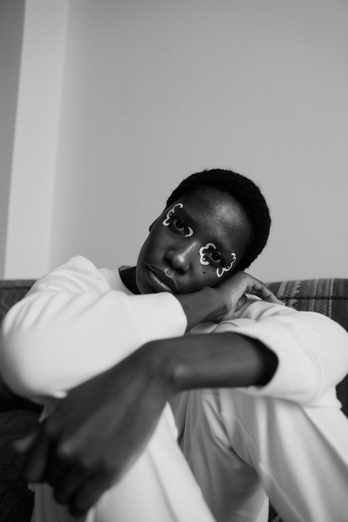 Stylish black and white portrait of a woman with unique face painting and contemplative expression.