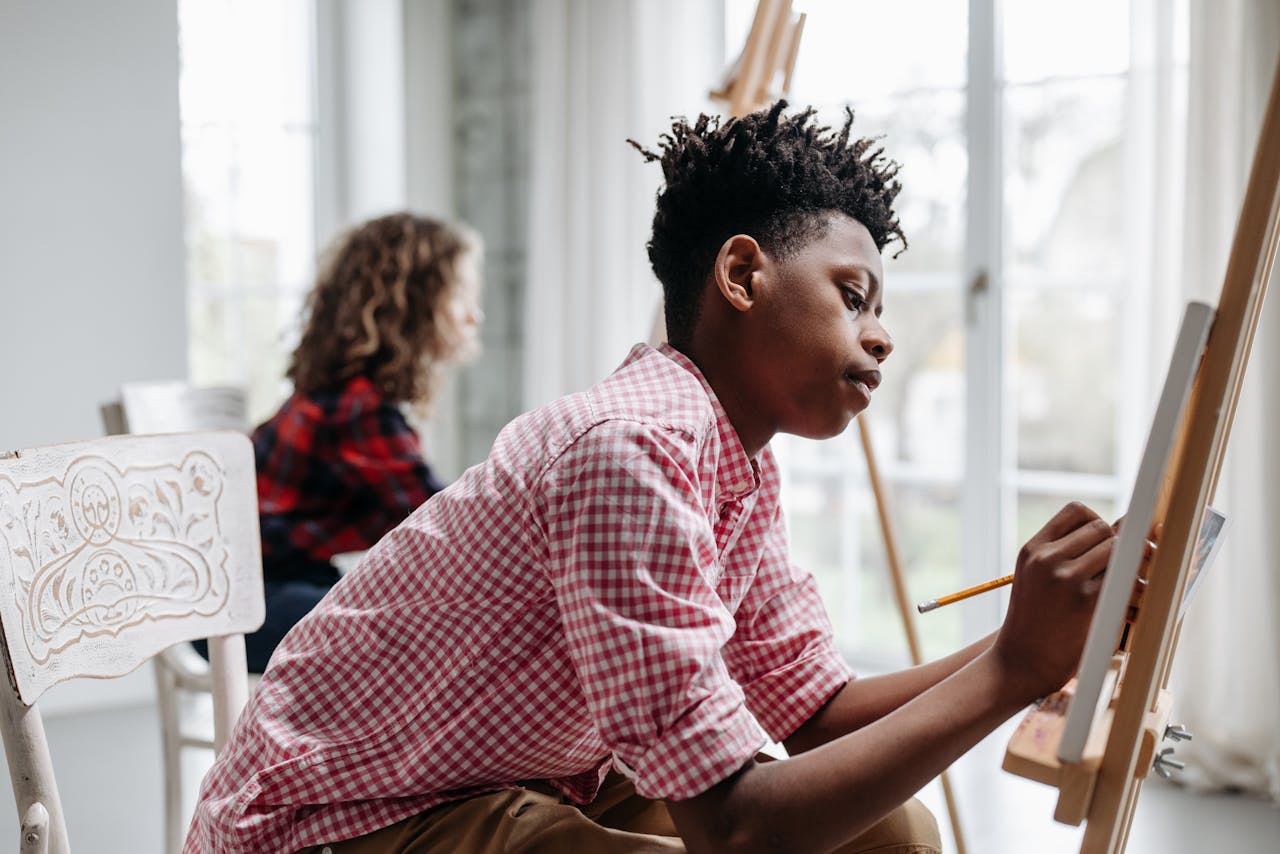 Two young artists concentrating on painting in a bright modern art studio.